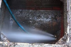 High pressure water jet cleaning a drain chamber